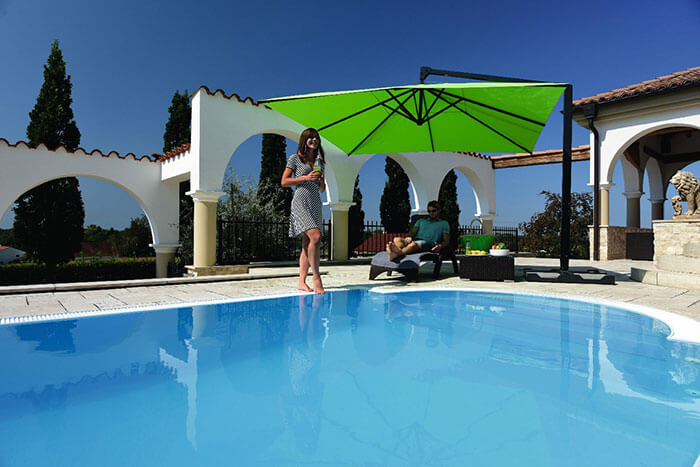 Frau unter CARAVITA Sonnenschirm an Pool