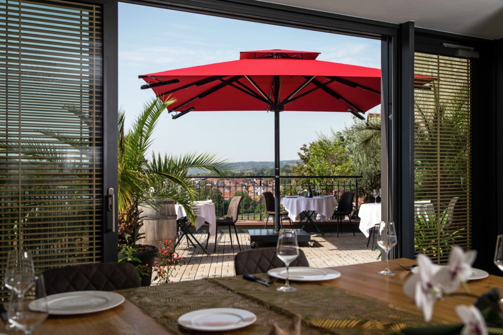 Caravita-Sonnenschirm auf Terrasse mit Tischen, Geschirr und Besteck